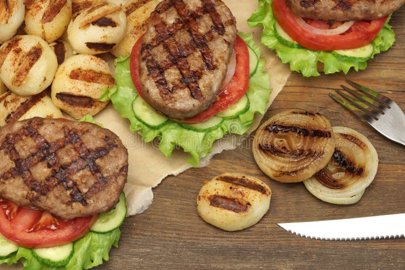 Обед с домодельными гамбургерами зажаренными BBQ на кухонном столе стоковая фотография Обед с домодельными гамбургерами зажаренными BBQ на кухонном столе стоковая фотография