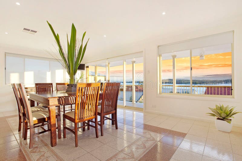 Table and chairs in luxurious tiled dining room with sunset visible through windows. Table and chairs in luxurious tiled dining room with sunset visible through windows.