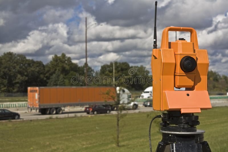 Survey on the highway - orange theodolite and semi-truck. Survey on the highway - orange theodolite and semi-truck.