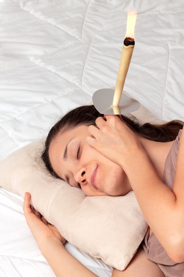 Shot of young woman having ear candle treatment. Shot of young woman having ear candle treatment