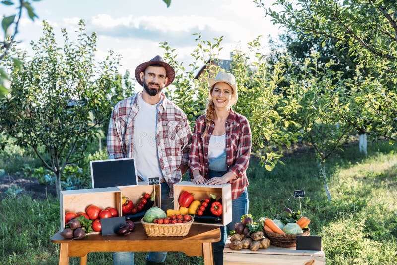 Two smiling farmers selling locally grown vegetables at market. Two smiling farmers selling locally grown vegetables at market