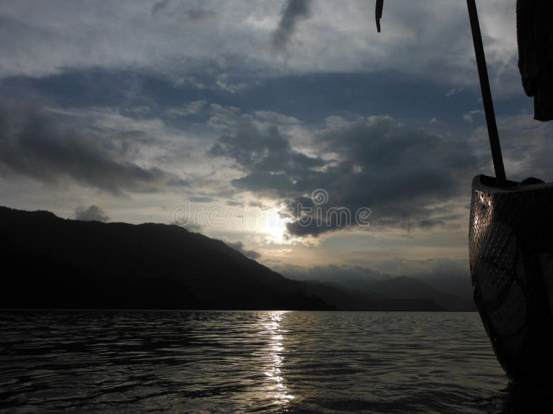 Озеро Pokhara на заходе солнца увиденном от шлюпки. Озеро и холмистый район Pokhara, Непала, увиденного от арендной шлюпки