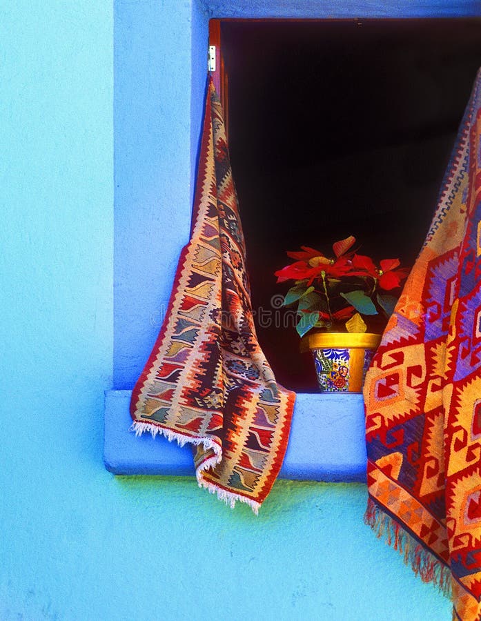 Open window with hanging woven rugs and a poinsettia in a painted pot for Christmas, in Oaxaca, Mexico. Open window with hanging woven rugs and a poinsettia in a painted pot for Christmas, in Oaxaca, Mexico