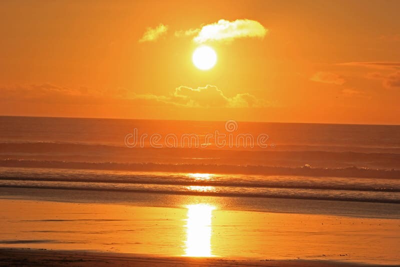 orange and yellow sunset at muriwai beach. orange and yellow sunset at muriwai beach