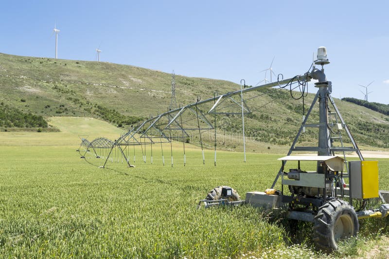 Center pivot irrigation system used to deliver precise quantities of water in a designated field area by moving in circle , with wind turbines in the background. Center pivot irrigation system used to deliver precise quantities of water in a designated field area by moving in circle , with wind turbines in the background