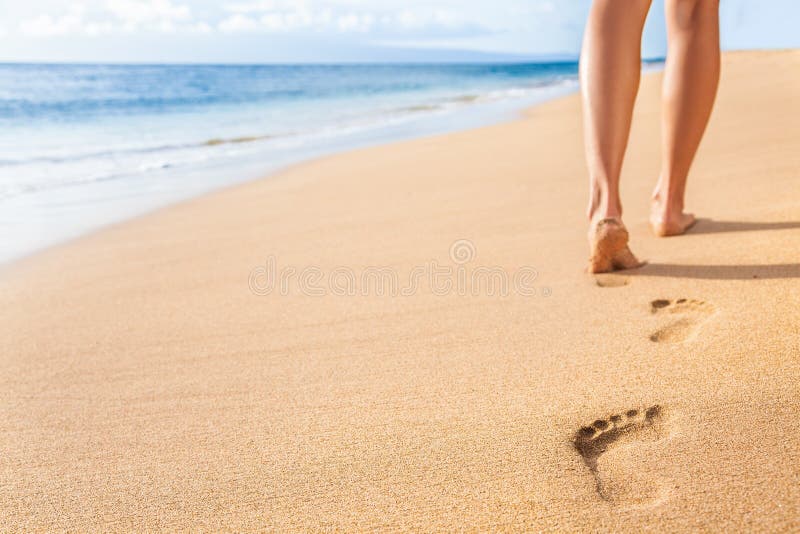 Beach travel - woman relaxing walking on sand beach leaving footprints in the sand. Closeup detail of female feet and legs on golden sand on Kaanapali beach, Maui, Hawaii, USA. Beach travel - woman relaxing walking on sand beach leaving footprints in the sand. Closeup detail of female feet and legs on golden sand on Kaanapali beach, Maui, Hawaii, USA.