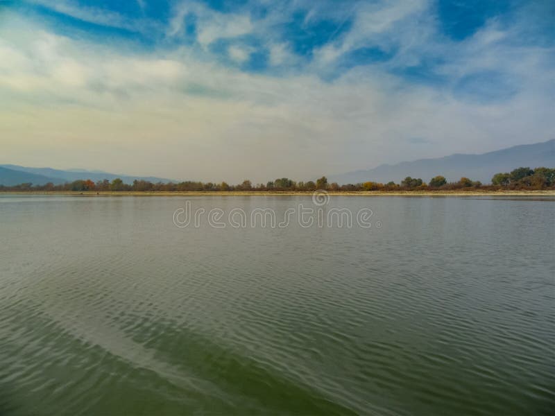 Осень на озере Kerkini - воде, небе и холмах одетых в тумане - фантазия нежных цветов Северная Греция стоковые фотографии rf Осень на озере Kerkini - воде, небе и холмах одетых в тумане - фантазия нежных цветов Северная Греция стоковые фотографии rf