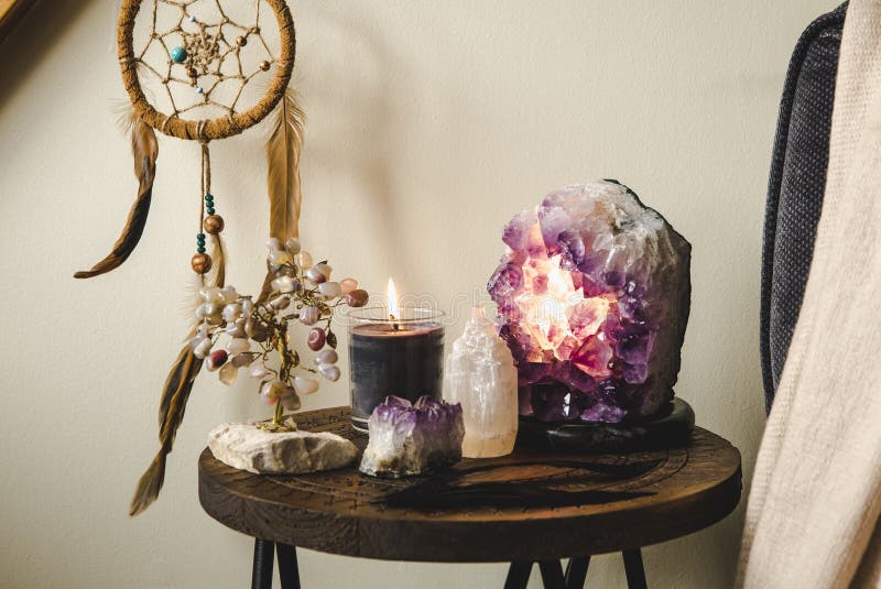 Relaxing home shrine with relaxing objects  amethyst cluster geode lamp illuminated  scented candle burning  selenite tower stone  crystal wire tree and dream catcher. Relaxing home shrine with relaxing objects  amethyst cluster geode lamp illuminated  scented candle burning  selenite tower stone  crystal wire tree and dream catcher.