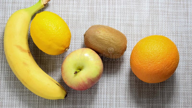остановить анимацию. несколько разных плодов передвигаются по поверхности. киви яблочный банан лимон апельсин.