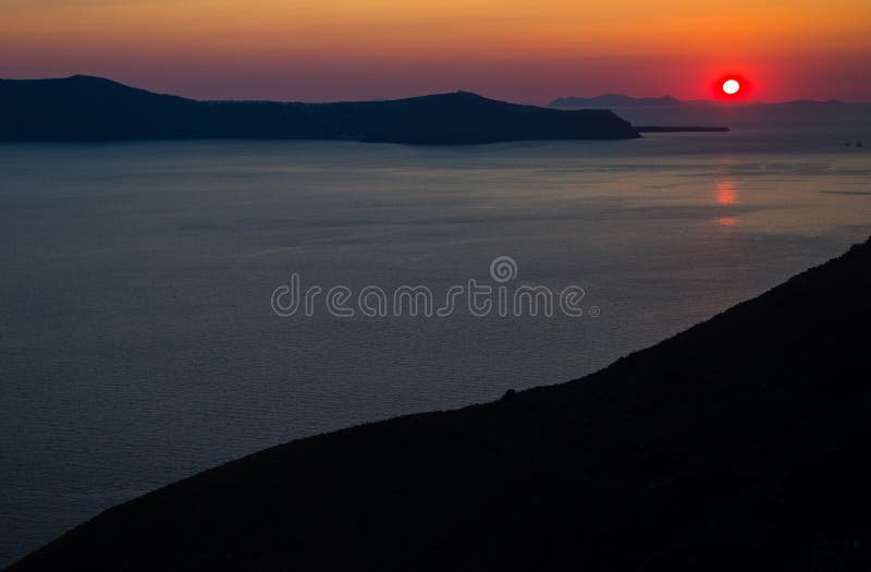 Остров Греция santorini Oia Естественный покрашенный заход солнца Темный - красное небо Заходящее солнце золота за горами Отражат стоковое изображение Остров Греция santorini Oia Естественный покрашенный заход солнца Темный - красное небо Заходящее солнце золота за горами Отражат стоковое изображение
