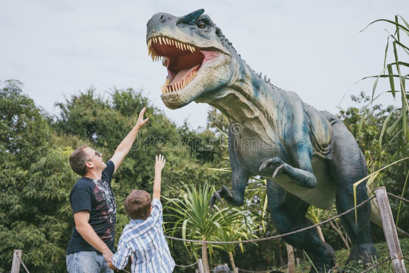 Отец и сын играя в парке dino приключения стоковые фотографии rf Отец и сын играя в парке dino приключения стоковые фотографии rf