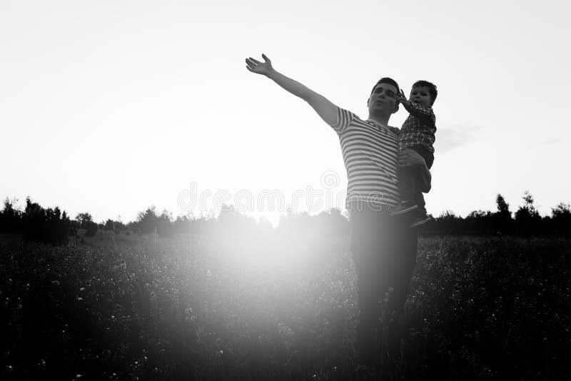 Father and son playing in field at the sunset time. Man holding little boy on hands and pointing to sky. Copy space for text. Father and son playing in field at the sunset time. Man holding little boy on hands and pointing to sky. Copy space for text.