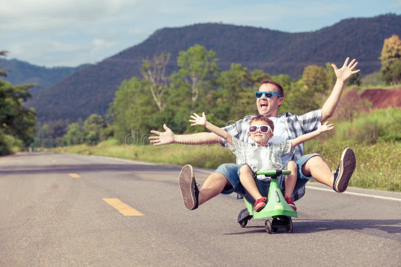 Father and son playing on the road at the day time. Concept of friendly family. Father and son playing on the road at the day time. Concept of friendly family.