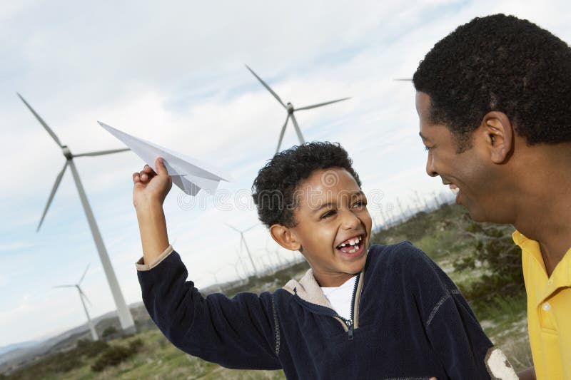 Father and son playing with paper plane at wind farm. Father and son playing with paper plane at wind farm