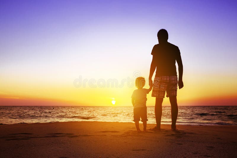 Father and son standing at sunset beach. Fatherhood concept with space for text. Father and son standing at sunset beach. Fatherhood concept with space for text