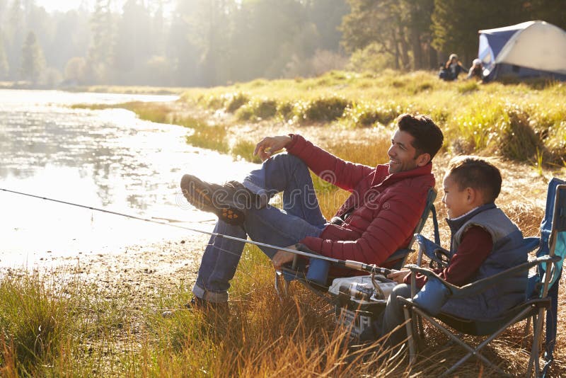 Father and son on a camping trip fishing by a lake. Father and son on a camping trip fishing by a lake