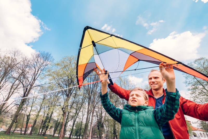 Father and son start to fly a kite in sky. Father and son start to fly a kite in sky