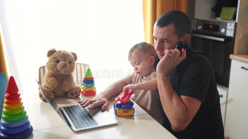 отец, работающий из дома с маленьким сыном на руках. концепция бизнеса на основе пандемии. отец пытается видеоматериал