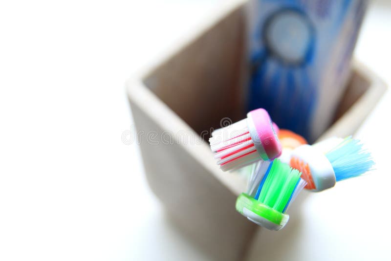Отмелый DOF снял 3 зубных щеток и зубных паст в tumbler глины в свете утра стоковое изображение rf Отмелый DOF снял 3 зубных щеток и зубных паст в tumbler глины в свете утра стоковое изображение rf