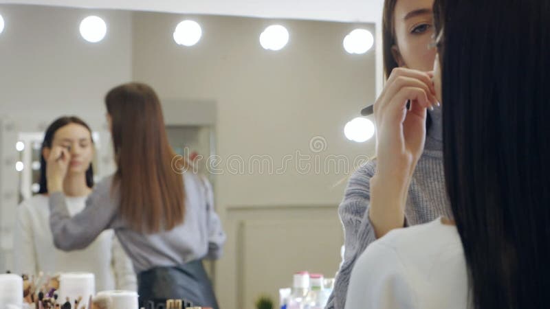 отражение в зеркале очаровательной девушки-макияжа делает макияж красивой девушке видеоматериал