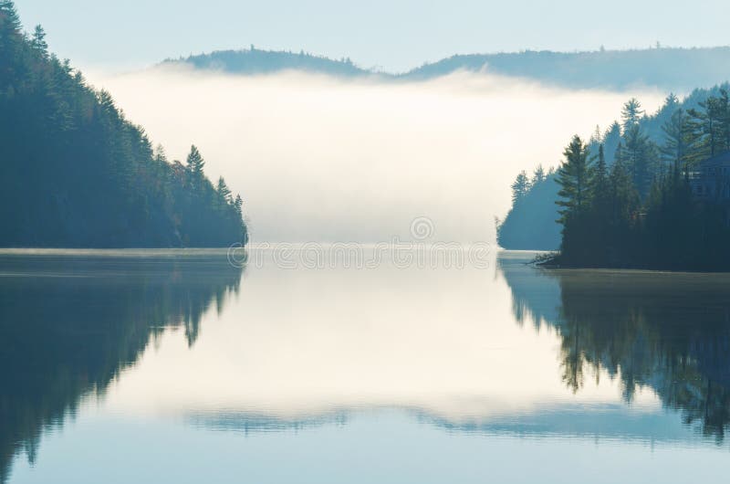 Reflection of morning fog rising on lake between mountains. Reflection of morning fog rising on lake between mountains