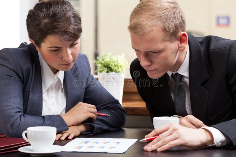 Young attractive businesspeople tracking survey results in cafe. Young attractive businesspeople tracking survey results in cafe