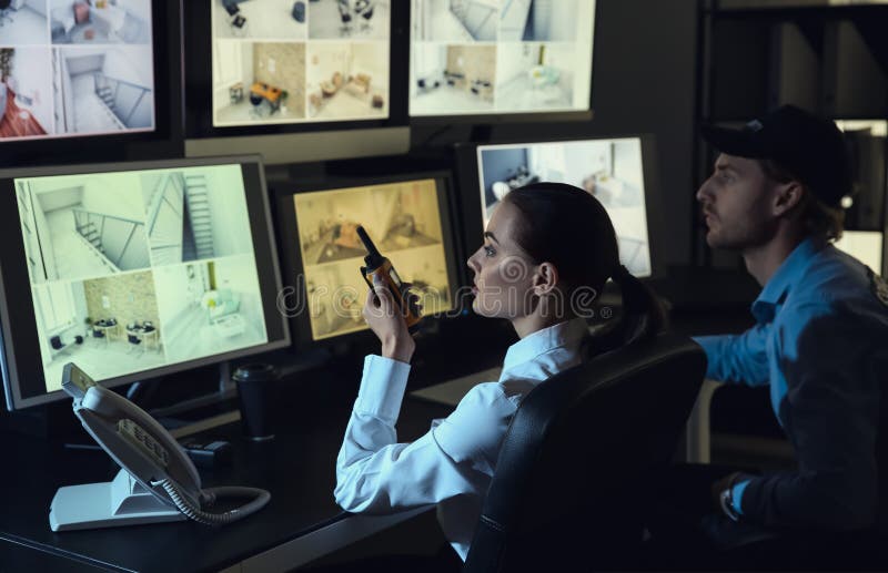 Охранники контролируя современные камеры CCTV в комнате наблюдения стоковое фото rf