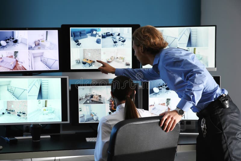 Охранники контролируя современные камеры CCTV в комнате наблюдения стоковая фотография rf