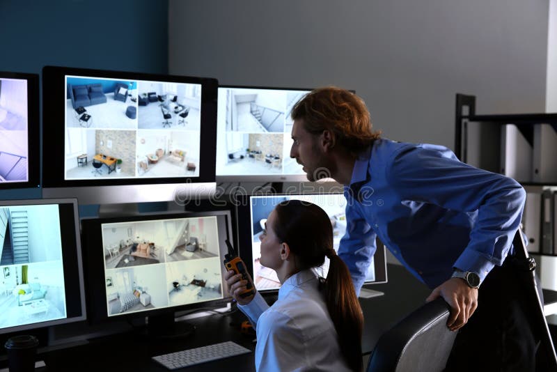 Охранники контролируя современные камеры CCTV в комнате наблюдения стоковая фотография