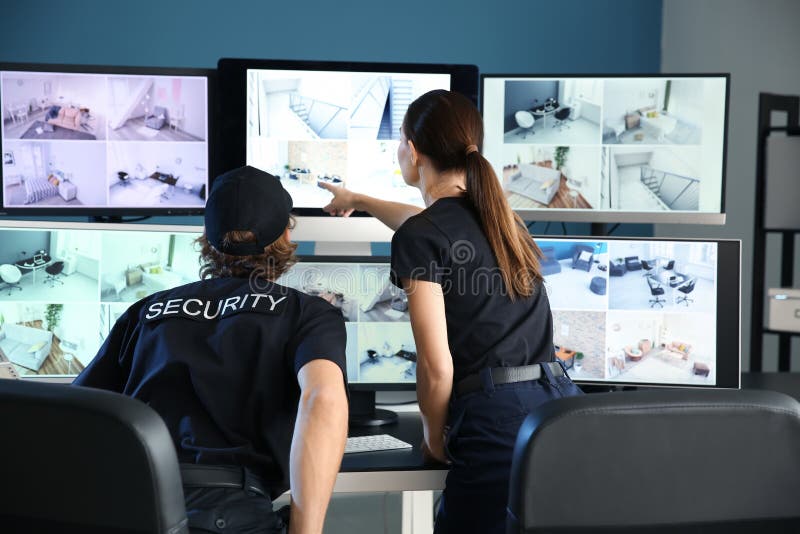 Охранники контролируя современные камеры CCTV в комнате наблюдения стоковые фотографии rf