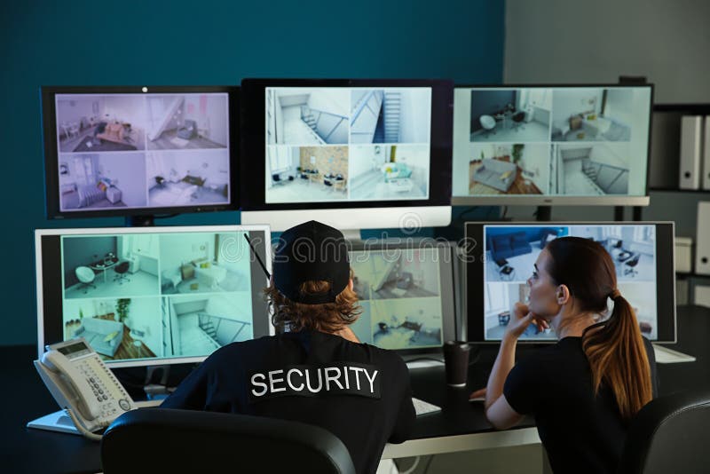 Охранники контролируя современные камеры CCTV в комнате наблюдения стоковые фото