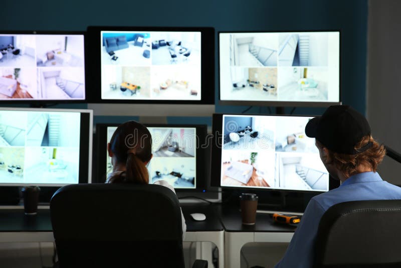 Охранники контролируя современные камеры CCTV в комнате наблюдения стоковое фото rf