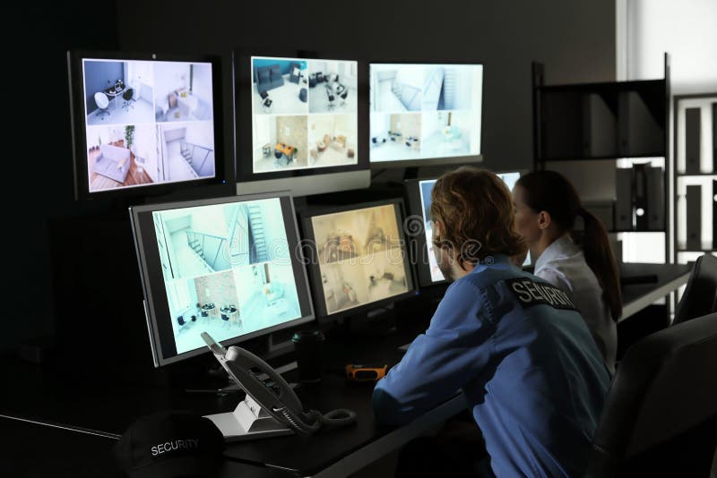 Охранники контролируя современные камеры CCTV в комнате наблюдения стоковые фото