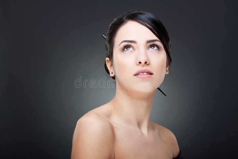 Beautiful face of a glamour woman with modern hairstyle and brightly makeup looking up. Beautiful face of a glamour woman with modern hairstyle and brightly makeup looking up