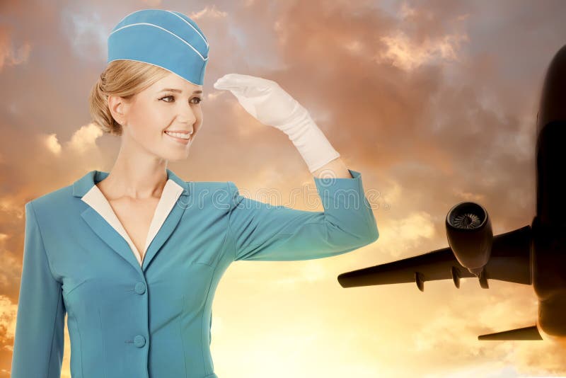 Очаровательный Stewardess одетый в голубой форме на предпосылке неба стоковое фото rf Очаровательный Stewardess одетый в голубой форме на предпосылке неба стоковое фото rf