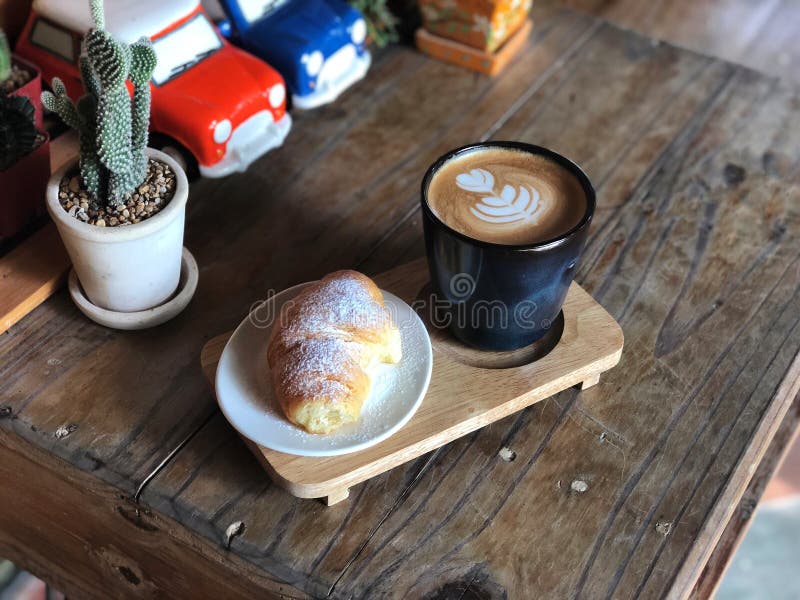 Очень вкусный завтрак; Кофе искусства Latte любов сердца в черных чашке и круассане покрыл с сахаром замороженности стоковые фото Очень вкусный завтрак; Кофе искусства Latte любов сердца в черных чашке и круассане покрыл с сахаром замороженности стоковые фото