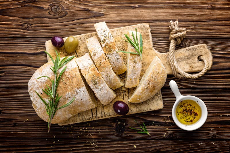Очень вкусный домодельный итальянский хлеб ciabatta с оливковым маслом и оливками на деревянной деревенской предпосылке, над взгл стоковые изображения rf Очень вкусный домодельный итальянский хлеб ciabatta с оливковым маслом и оливками на деревянной деревенской предпосылке, над взгл стоковые изображения rf