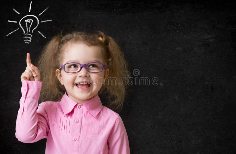 Kid in glasses with idea lamp on school chalkboard in classroom. Kid in glasses with idea lamp on school chalkboard in classroom