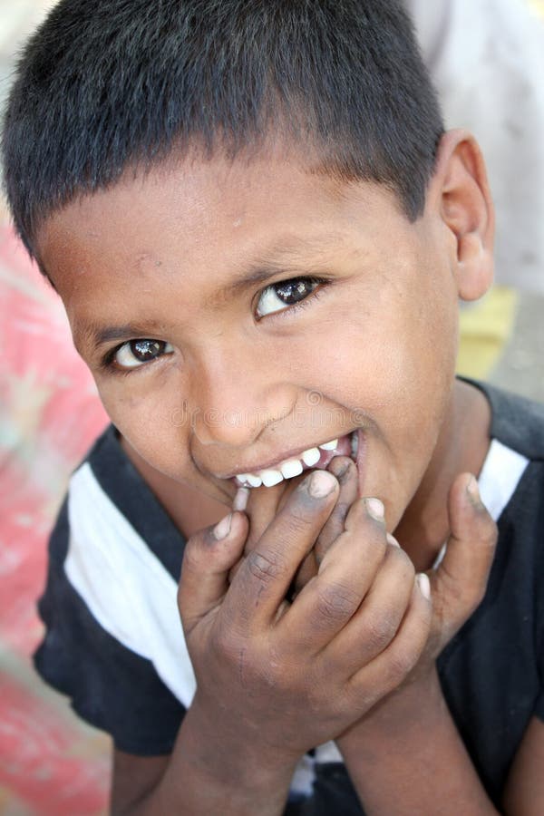 A portrait of a shy poor kid from India putting dirty fingers in his mouth. A portrait of a shy poor kid from India putting dirty fingers in his mouth.