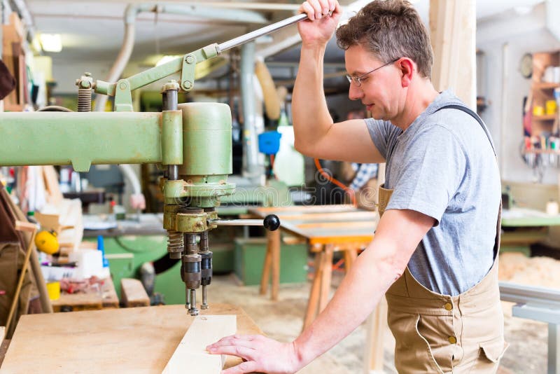 Плотник используя электрический сверлильный аппарат в плотничестве ...