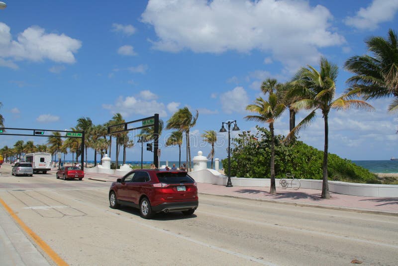 Cars travel northbound on State Road A1A at Las Olas Boulevard at Fort Lauderdale, Florida Beach in a warm April spring afternoon under palm trees and a partly cloudy blue sky. Cars travel northbound on State Road A1A at Las Olas Boulevard at Fort Lauderdale, Florida Beach in a warm April spring afternoon under palm trees and a partly cloudy blue sky.