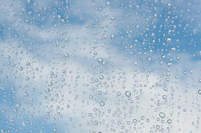 Drops of water on a window with blue sky and white clouds background. Drops of water on a window with blue sky and white clouds background