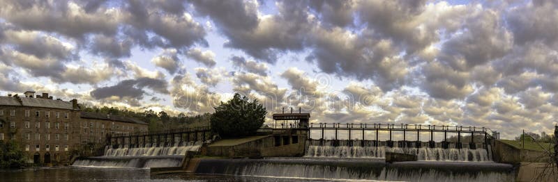 Prattville, Alabama, March 25, 2016: Panoramic view of the mill pond waterfall and Pratt Gin Factory building with dramatic cloud sky. Prattville, Alabama, March 25, 2016: Panoramic view of the mill pond waterfall and Pratt Gin Factory building with dramatic cloud sky.