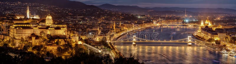 Панорама ночи города Будапешта - столицы Венгрии Здание на праве, холм парламента замка Buda на левом и цепном мосте в m стоковое фото rf Панорама ночи города Будапешта - столицы Венгрии Здание на праве, холм парламента замка Buda на левом и цепном мосте в m стоковое фото rf
