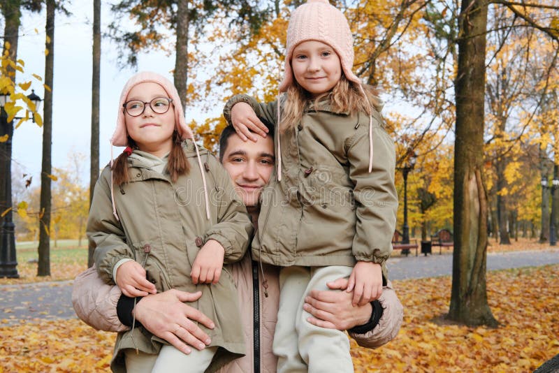 Dad is holding two girls in his arms. Family spending time together in the park. Horizontal photo. Dad is holding two girls in his arms. Family spending time together in the park. Horizontal photo