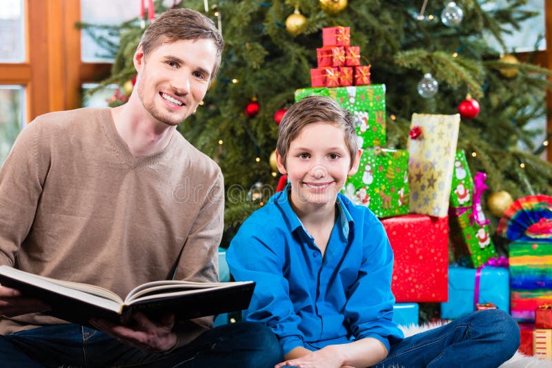 Папа читая вне от книги для ребенк под деревом X-mas стоковое изображение