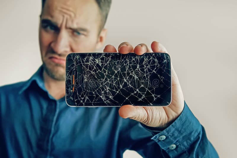 Парень держит черный smartphone с сломленным дисплеем стоковые изображения rf Парень держит черный smartphone с сломленным дисплеем стоковые изображения rf