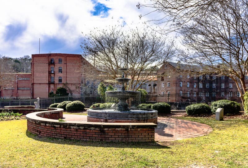 Prattville, Alabama, USA - January 28, 2017: A view of the fountain in Heritage Park in downtown Prattville overlooking the old Daniell Pratt Cotton Gin Company. Prattville, Alabama, USA - January 28, 2017: A view of the fountain in Heritage Park in downtown Prattville overlooking the old Daniell Pratt Cotton Gin Company.