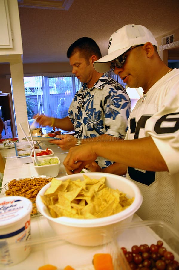 Two young adult men getting some food at the house party. Two young adult men getting some food at the house party.