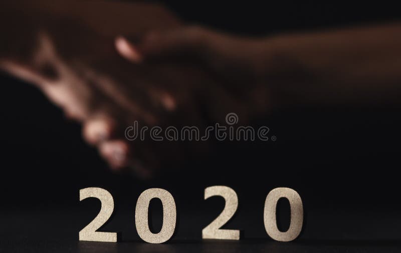Партнеры пожимают руки на заднем плане в новом 2020 году, деревянные фигуры даты на черном фоне, концепция бизнеса и стоковые изображения rf Партнеры пожимают руки на заднем плане в новом 2020 году, деревянные фигуры даты на черном фоне, концепция бизнеса и стоковые изображения rf